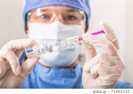 A medical worker putting SARS-CoV-2 vaccine against the coronavirus into an injection 71403132