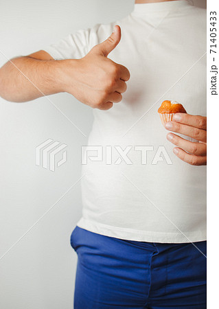 Overweight man snacking with cupcake 71405433