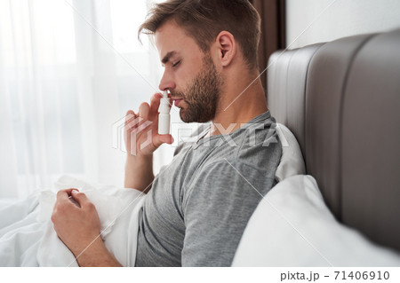 Man using nasal spray to help himself 71406910