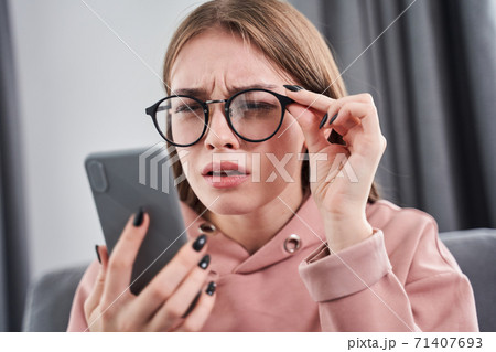 Woman wearing glasses squinting her eyes Woman wearing glasses squinting her eyes 71407693
