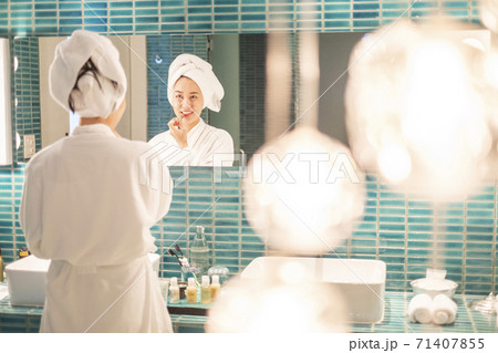 Young woman putting on makeup after shower 71407855