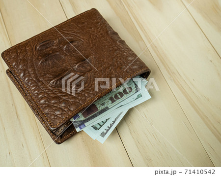 Crocodile leather wallet and banknote on wood table. Crocodile leather wallet and banknote on wood table. 71410542