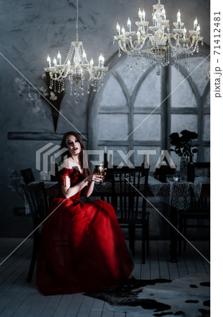 Bloodthirsty female vampire in red dress. Medieval interior Bloodthirsty female vampire in red dress. Medieval interior 71412481