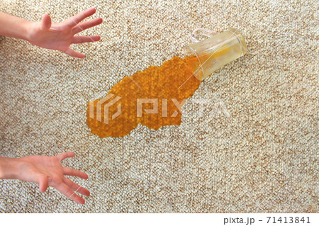 Glass of juice fell on carpet. Drink spilled on floor. 71413841