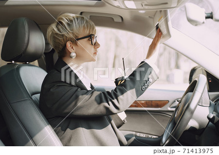 Businesswoman sitting inside a car and drinksa coffee 71413975