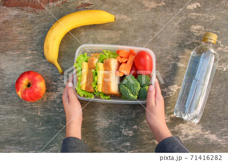 Sandwiches, fruits and vegetables in food box, water on old wooden background. Top view. 71416282