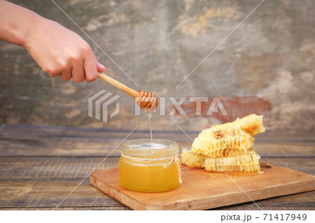 Honey in a jar and honeycomb on an old wooden background. Honey in a jar and honeycomb on an old wooden background. 71417949
