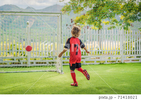 Little cute kid boy in red football uniform playing soccer, football on field, outdoors. Active child making sports with kids or father, Smiling happy boy having fun in summer Little cute kid boy in red football uniform playing soccer, football on field, outdoors. Active child making sports with kids or father, Smiling happy boy having fun in summer 71418021