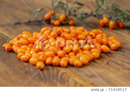 Many sea buckthorn, hippophae rhamnoides, berries on wooden table. 71418517