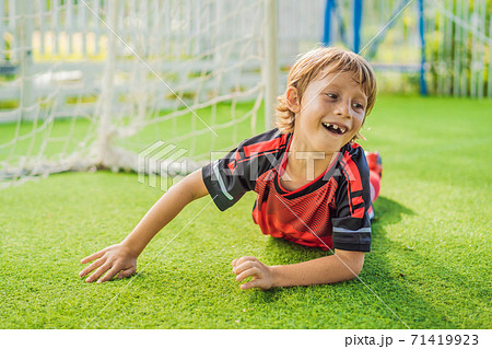 Little cute kid boy in red football uniform playing soccer, football on field, outdoors. Active child making sports with kids or father, Smiling happy boy having fun in summer Little cute kid boy in red football uniform playing soccer, football on field, outdoors. Active child making sports with kids or father, Smiling happy boy having fun in summer 71419923