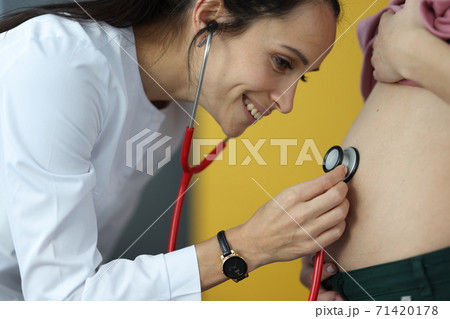 Doctor listens with stethoscope to the belly of pregnant woman Doctor listens with stethoscope to the belly of pregnant woman 71420178