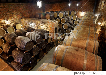 Rows of alcoholic barrels are kept in stock. Distillery. Cognac, whiskey, wine, brandy. Alcohol in barrels, alcohol storage Rows of alcoholic barrels are kept in stock. Distillery. Cognac, whiskey, wine, brandy. Alcohol in barrels, alcohol storage 71421358