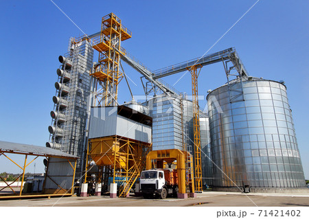 Agricultural silo truck of orange color on the territory of grain storage in sunny weather. Agricultural silo truck of orange color on the territory of grain storage in sunny weather. 71421402