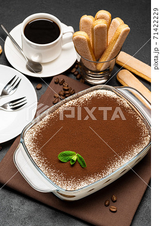 Traditional Italian Tiramisu dessert in glass baking dish and cup of fresh hot espresso coffee on concrete background 71422229