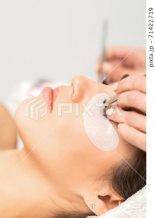 Woman having eyelash extension procedure Woman having eyelash extension procedure 71422719