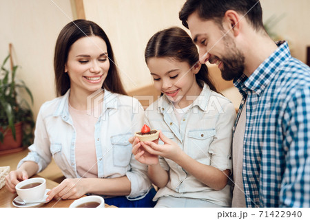 Young Happy Family Eating Cakes in Cafeteria. 71422940