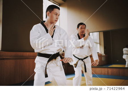 Men stand in a rack and practice karate techniques Men stand in a rack and practice karate techniques 71422964