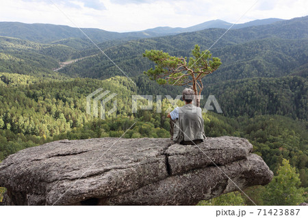 Man sitting on a rock near pine tree, Altai Man sitting on a rock near pine tree, Altai 71423887