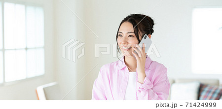 テレワーク リビングでスマホで会話する笑顔の若い女性 バナーサイズ テレワーク リビングでスマホで会話する笑顔の若い女性 バナーサイズ 71424999
