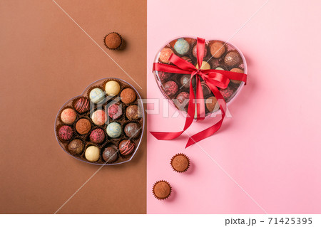 Chocolate candies truffle in a heart shape box on a pink background. 71425395