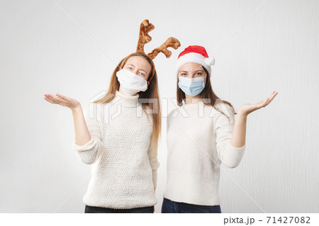 Caucasiam young women on white background with santa hat and reindeer. Christmas quarantine 71427082