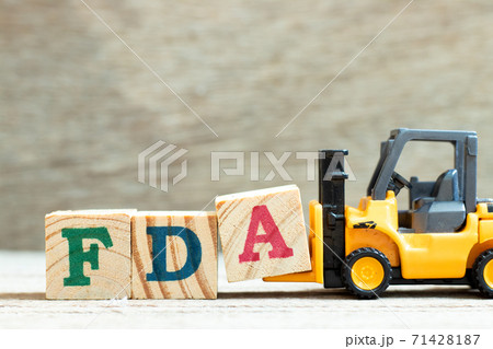 Toy forklift hold letter block A to complete word FDA (abbreviation of food and drug administration) on wood background Toy forklift hold letter block A to complete word FDA (abbreviation of food and drug administration) on wood background 71428187