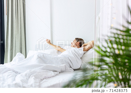 Woman is waking up in the bed in her bedroom 71428375