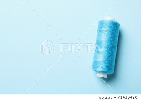 Blue sewing thread on blue background, space - Stock Photo