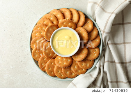 Napkin and plate with cracker biscuits and cheese sauce on white - light beige background 71430656