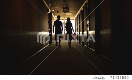 Back view of Caucasian young couple walking hotel hallway Back view of Caucasian young couple walking hotel hallway 71432639
