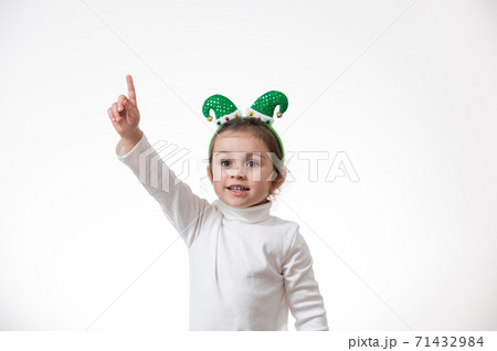 The girl with the hoop in the form of an elf hat on her head shows her finger up. The girl with the hoop in the form of an elf hat on her head shows her finger up. 71432984