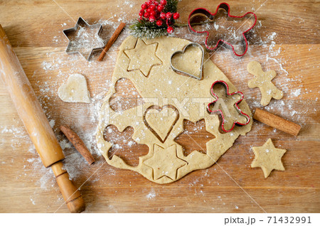 Still life, a top view of a kitchen board with rolled out dough, raw gingerbread preparations, cinnamon sticks and Christmas decoration. Still life, a top view of a kitchen board with rolled out dough, raw gingerbread preparations, cinnamon sticks and Christmas decoration. 71432991