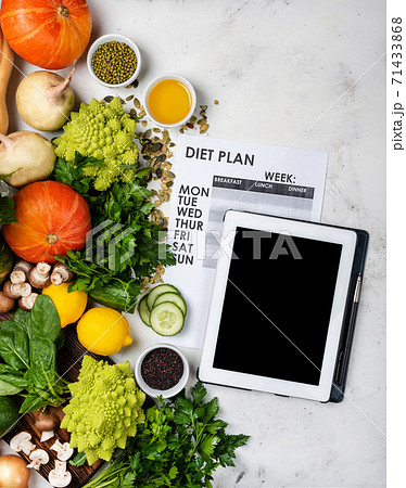 Tablet computer Diet plan on the sheet and different vegetables and greens. 71433868