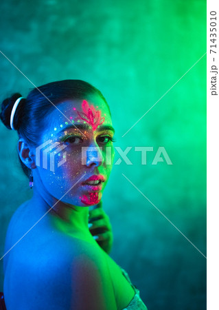Portrait of woman in fluorescent paint in neon lighting. 71435010