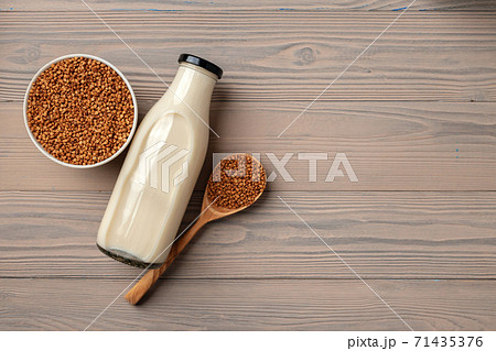 Buckwheat milk concept with bottle of milk and buckwheat grain in bowl 71435376