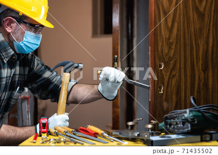 Carpenter at work protects the face with the surgical mask. Covid-19 prevention. Carpenter at work protects the face with the surgical mask. Covid-19 prevention. 71435502