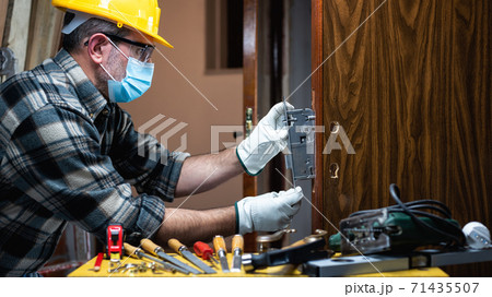Carpenter at work protects the face with the surgical mask. Covid-19 prevention. Carpenter at work protects the face with the surgical mask. Covid-19 prevention. 71435507