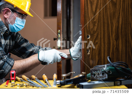 Carpenter at work protects the face with the surgical mask. Covid-19 prevention. 71435509