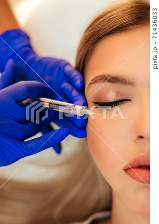 Beautiful woman gets an injection in her face. she has fashion make up and red shining lips 71436033