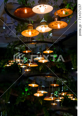 several round pendant retro loft style lanterns with edison bulbs shine with warm light in interior of dark restaurant, closeup of hanging lamps, nobody. loft-style restaurant with lighting fixtures. 71437137