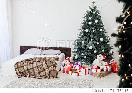 New Year's card bedroom interior with red bed decor and Christmas tree with gifts 71438118