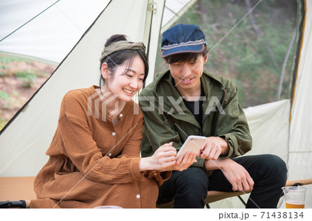 キャンプ場でスマホを使うアジア人男女 キャンプ場でスマホを使うアジア人男女 71438134