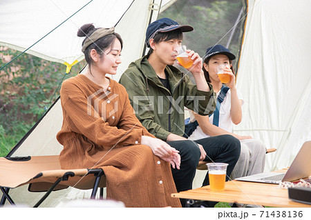 キャンプ場でノートパソコンを使ってリモートワークするアジア人男女 71438136