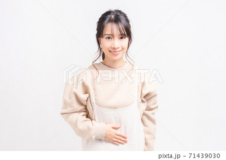 お腹に手を当てる若い女性 71439030