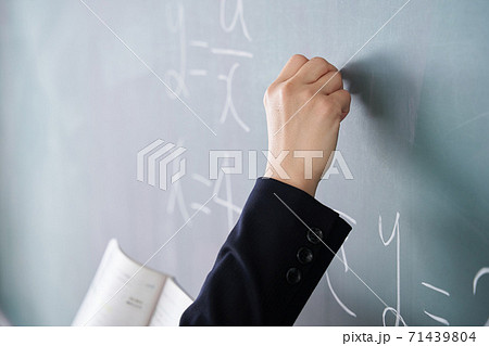 教室で黒板に文字を書く日本人女性教師の写真素材