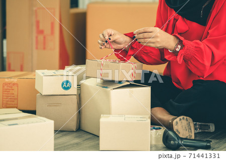 Online seller works at home office and packs shipping delivery box to customer. 71441331