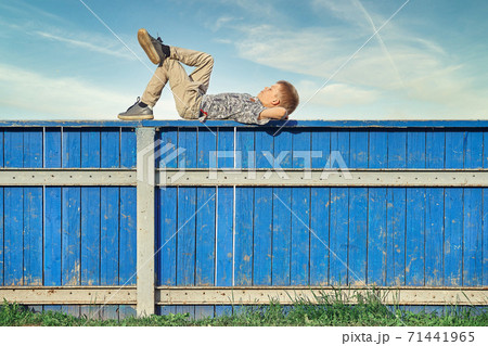 Boy resting and dreaming on hockey rink fence against cloudy sky Boy resting and dreaming on hockey rink fence against cloudy sky 71441965