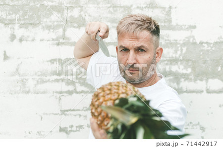 Stylish caucasian attractive chef with pineapple on a brick wall background. 71442917