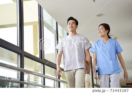 happy young asian physical therapists walking talking in hallway of nursing home 71443167