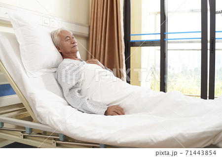 asian elderly male patient lying in bed sleeping in hospital ward or assisted living facility 71443854